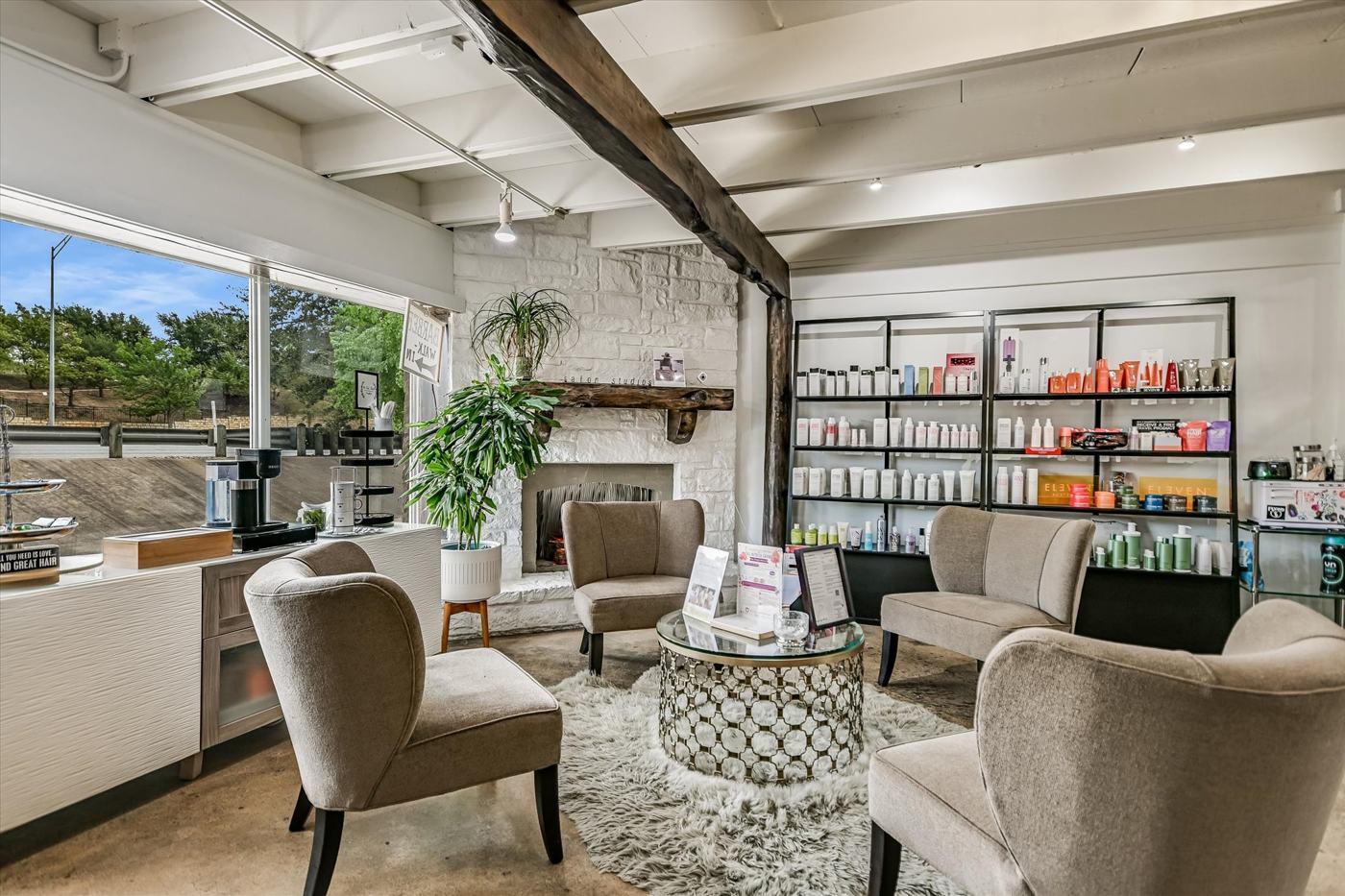 Suite 103 — salon reception under exposed timber beams and a stone fireplace